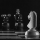A white knight chess piece faces down a row of black pieces